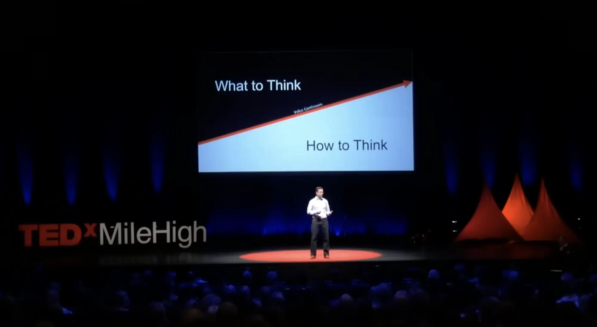 Mike Vaughan speaking on the TEDxMileHigh stage in front of a slide reading What to Think and How to Think